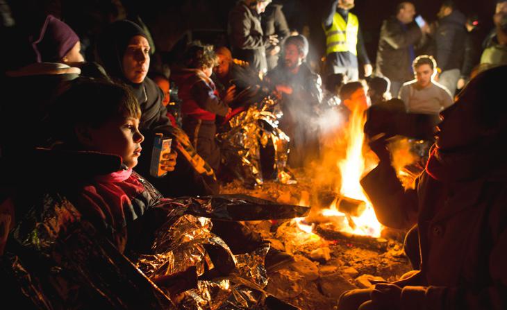 Niños pequeños se calientan junto a hogueras en el campamento de refugiados de Lesbos