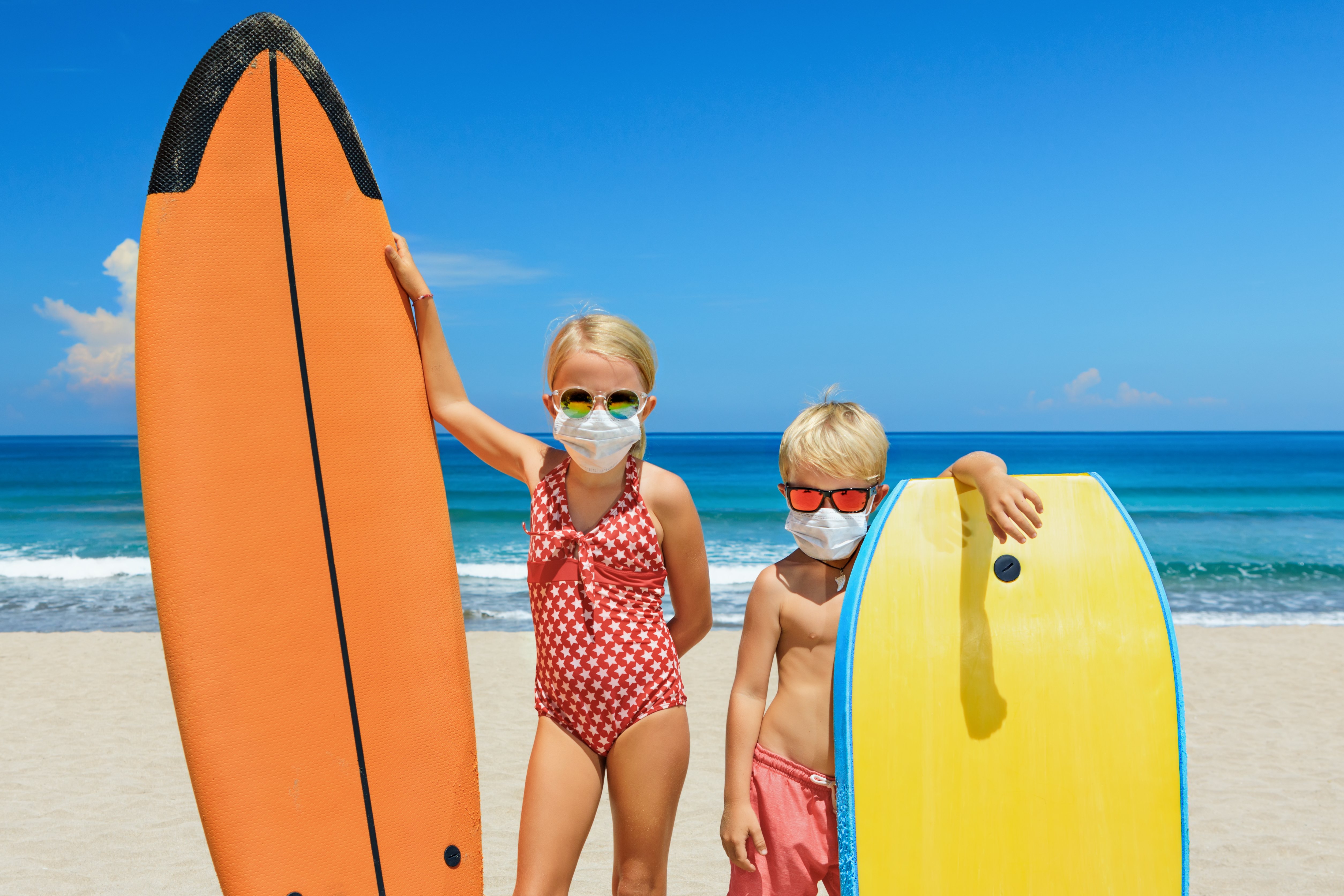 Jóvenes surfistas con tablas de surf usan máscaras protectoras en la playa.