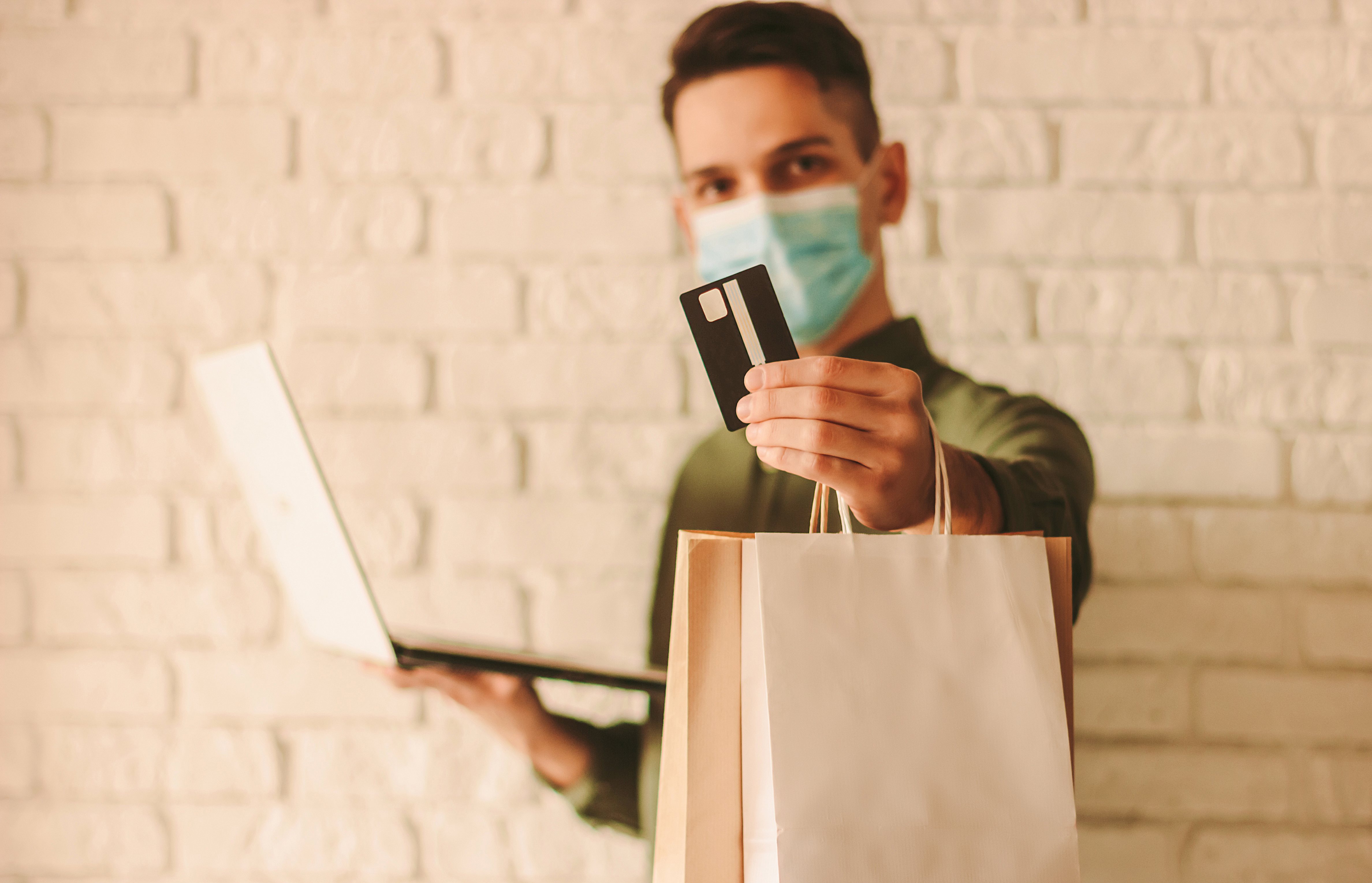 Hombre feliz con la máscara protectora haciendo compras en la tienda de internet.