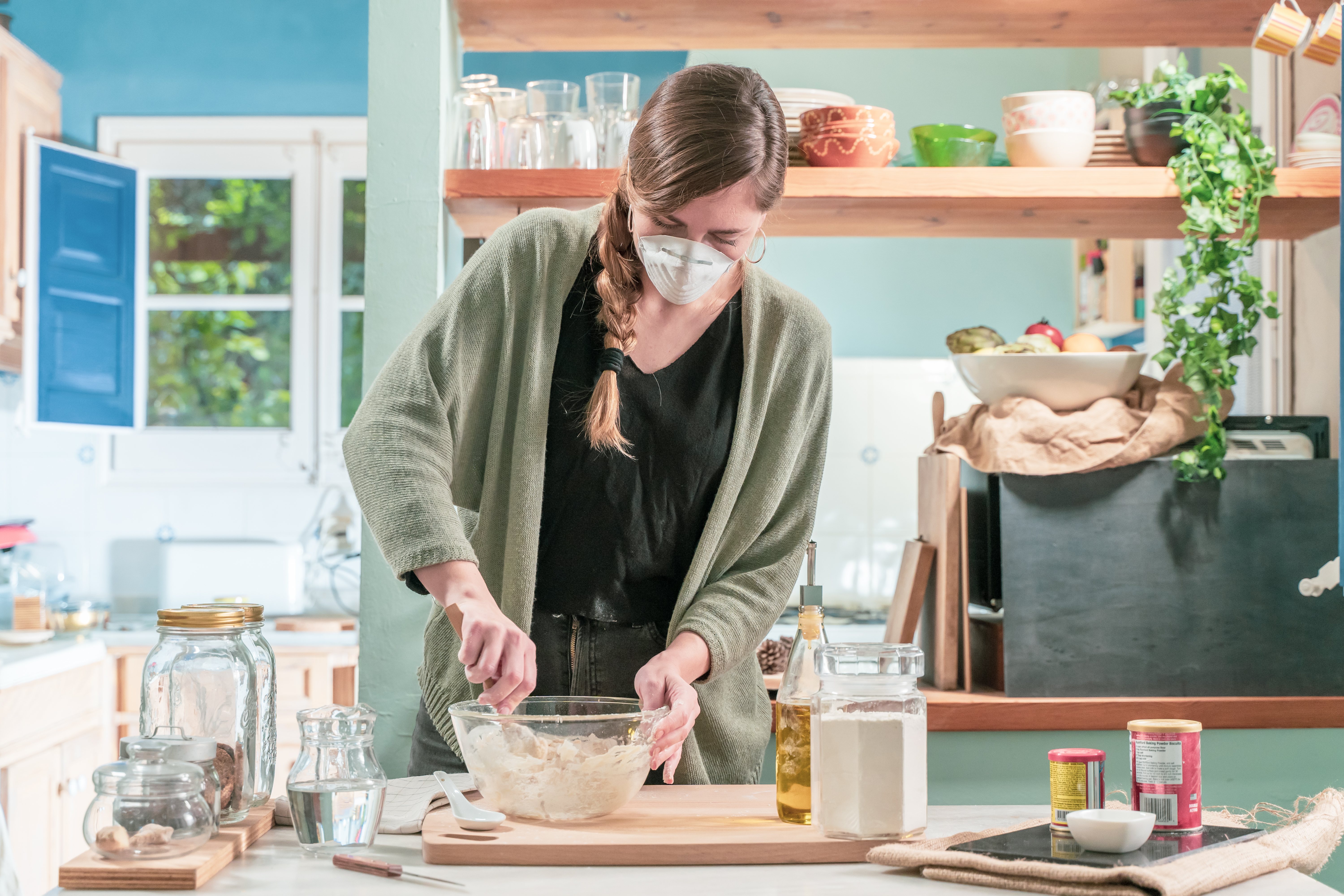 Mujer guapa aislada con mascarilla en cuarentena cocina en casa durante la crisis del coronavirus. Preciosa cocina rústica