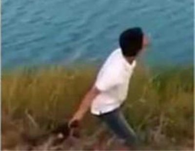 Un joven lanza a un perro a un lago lleno de cocodrilos
