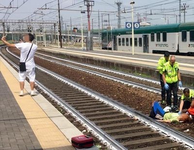 Un chico se hace un selfie con el símbolo de 'victoria' ante una mujer arrollada por un tren