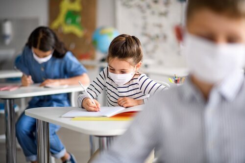 Niños y niñas con mascarilla en el colegio