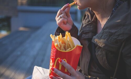 Mujer comiendo patatas de McDonald