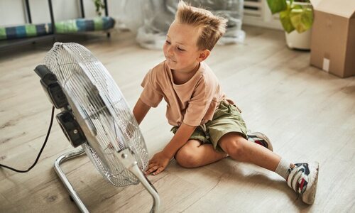 Niño sentado delante de un ventilador