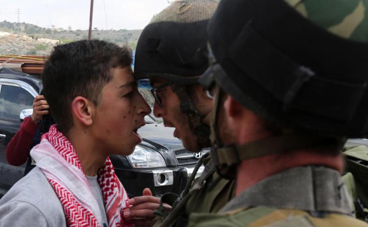 Un joven palestino grita a un solado israelí en el Día de la Tierra Palestina