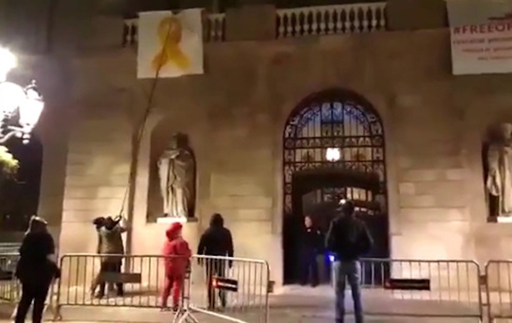 Un grupo de activistas encapuchados retiran el lazo amarillo del Ayuntamiento de Barcelona