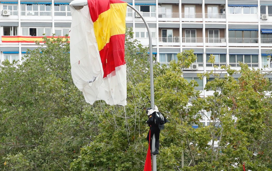 Un paracaidista se estampa con una farola en el desfile del Día de la Hispanidad