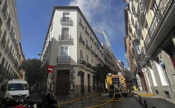 Los bomberos intentan apagar un incendio que afecta a dos viviendas en pleno centro de Madrid