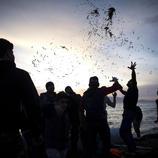 Un grupo de refugiados celebra su llegada a la costa