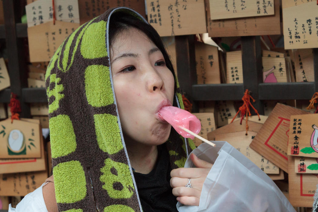 Una mujer se come una piruleta con forma de falo con motivo del Kanamara Matsuri