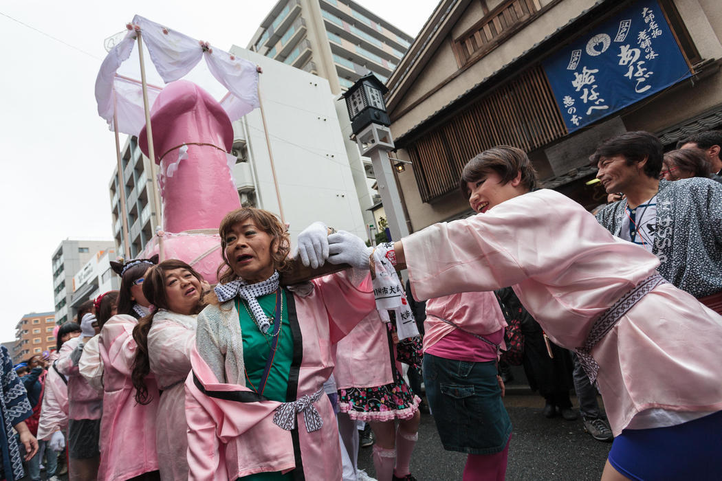 Un grupo de travestis llevan un paso con un enorme falo rosa en su interior