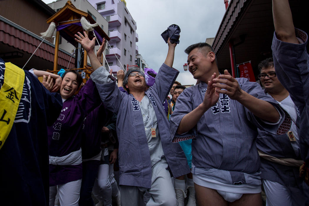 Un grupo de personas cantan y bailan alrededor del mikoshi