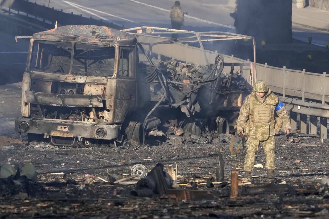 Soldado ucraniano entre los escombros de un camión militar en llamas en una calle de Kiev